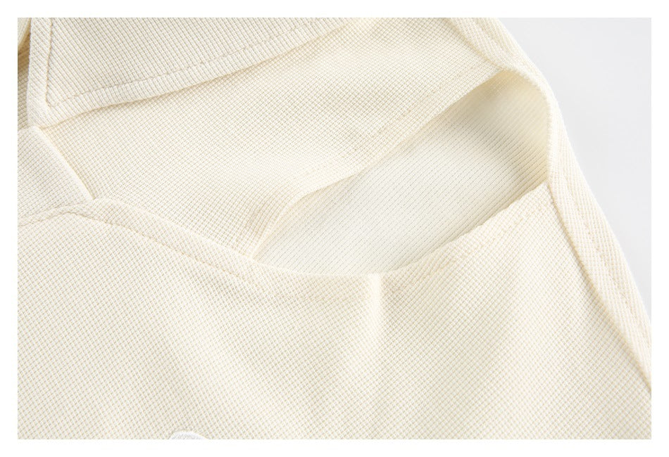 Close-up of the cream garment's folded collar and textured fabric.