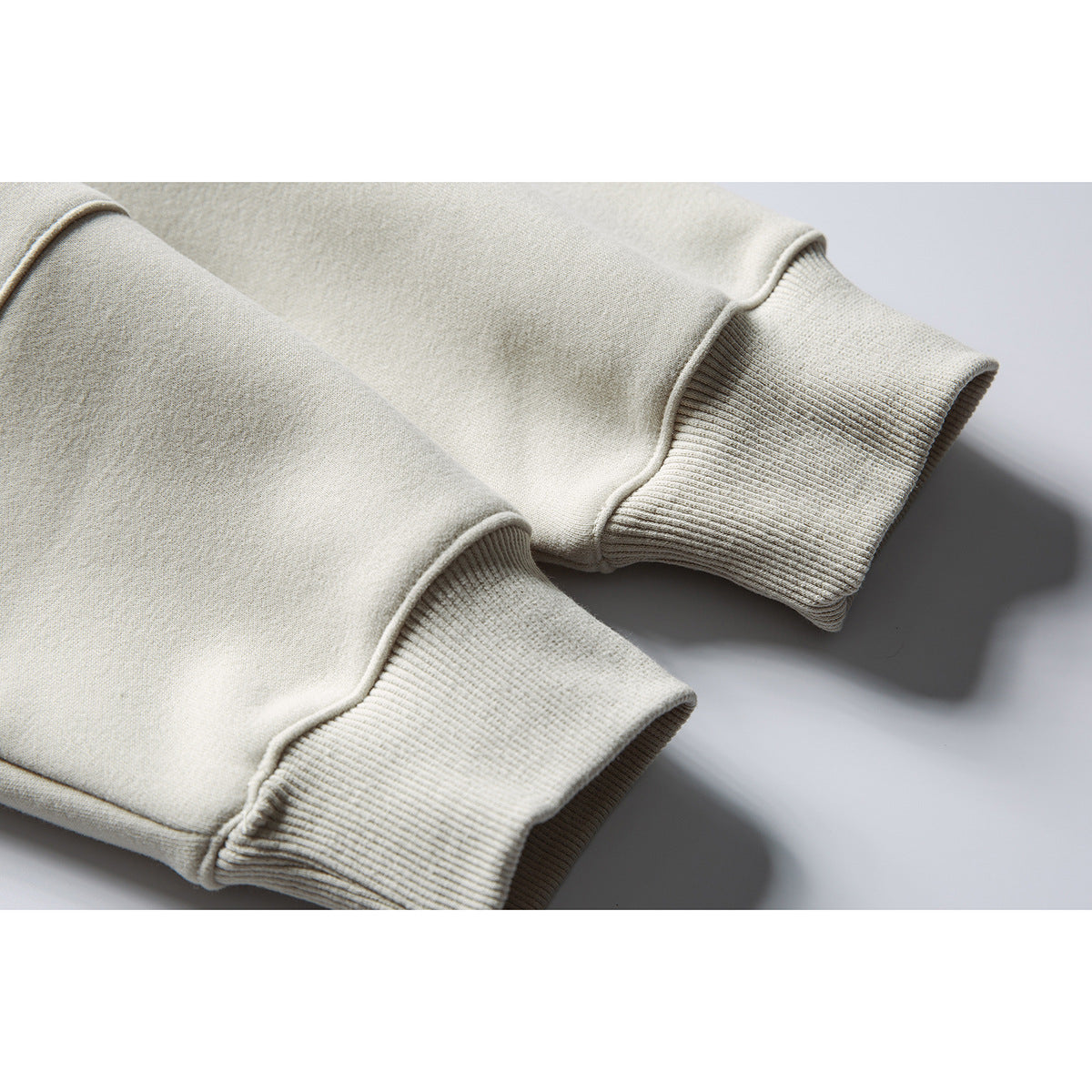 Close-up of the ribbed cuffs and stitched seams on a light beige sweatshirt.