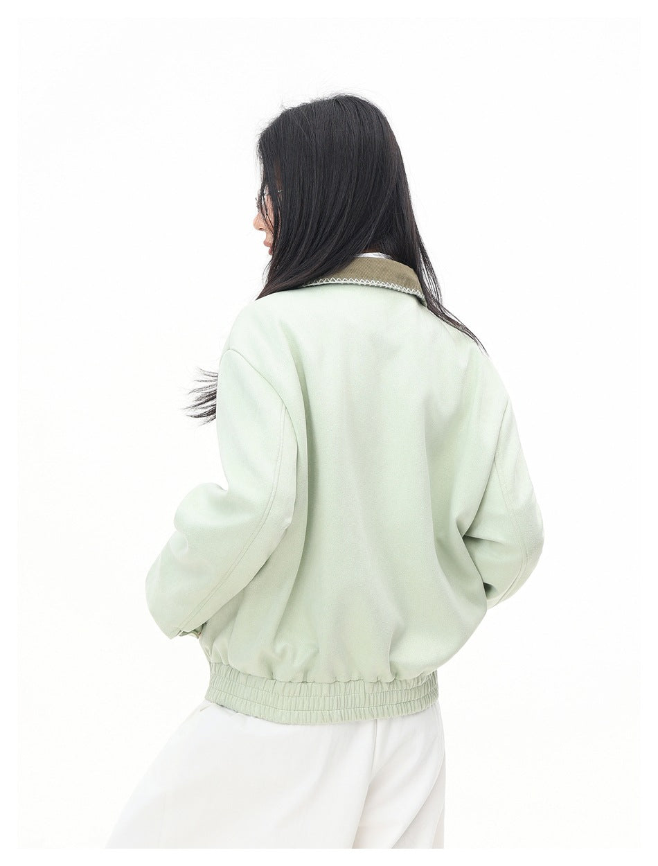 Back view of a model wearing a pale mint jacket with a brown contrast collar and gathered elastic hem.