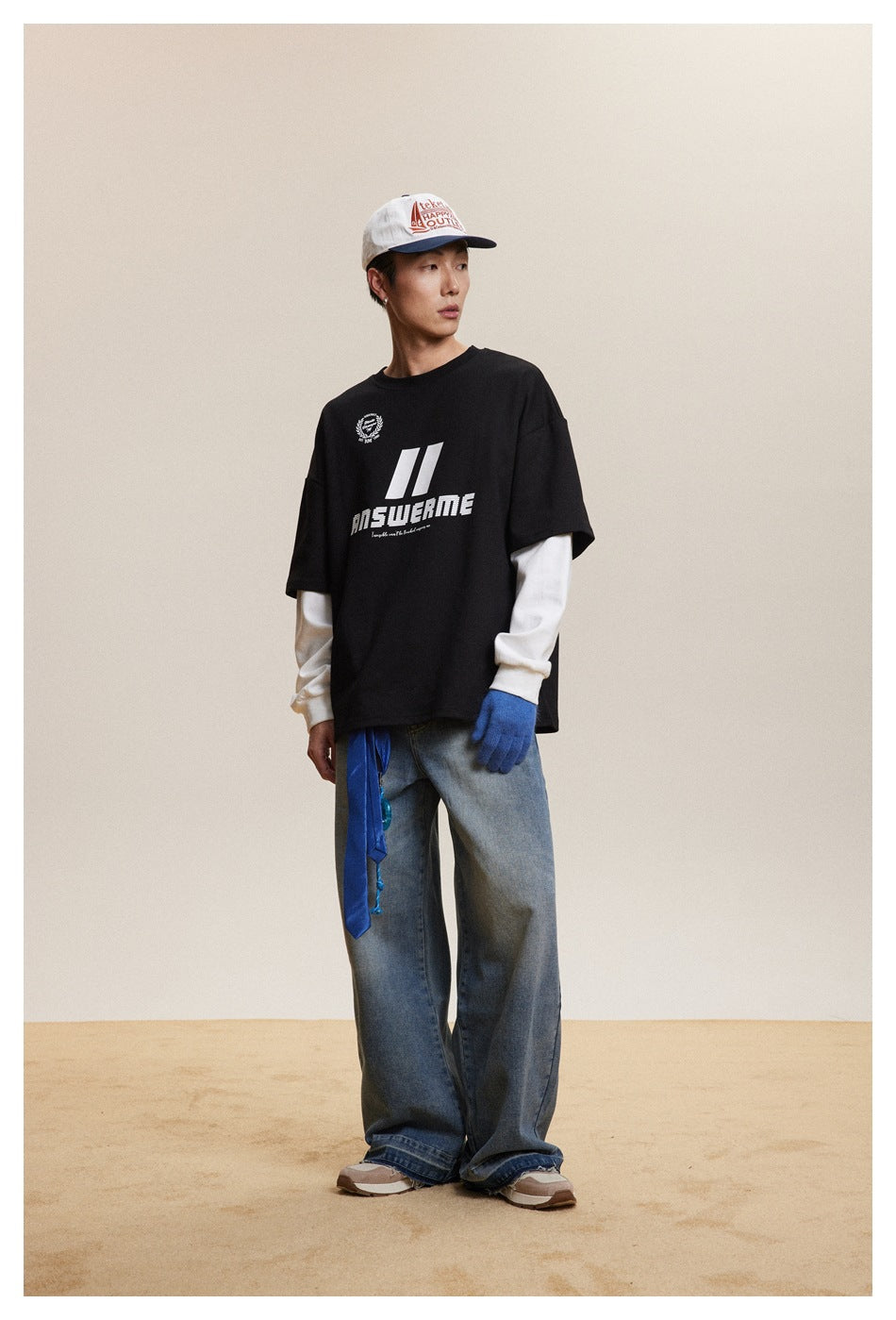 Model in black layered-look top with white sleeves and chest graphic, turned slightly sideways, wide-leg jeans