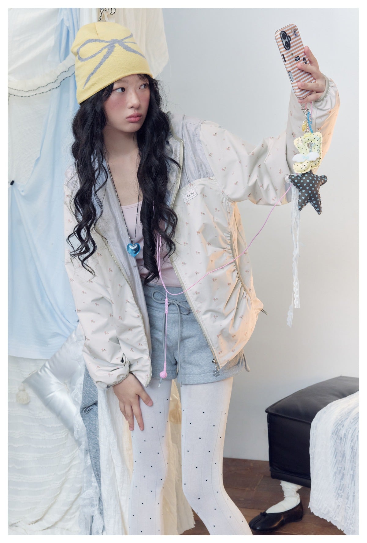 Model in a pale floral zip jacket and gray shorts, showing the jacket front and chest label.
