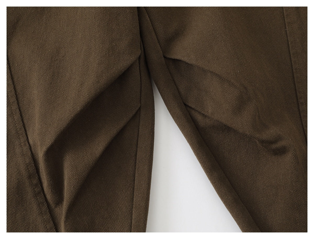 Close-up of brown trouser legs and seams against a white background.