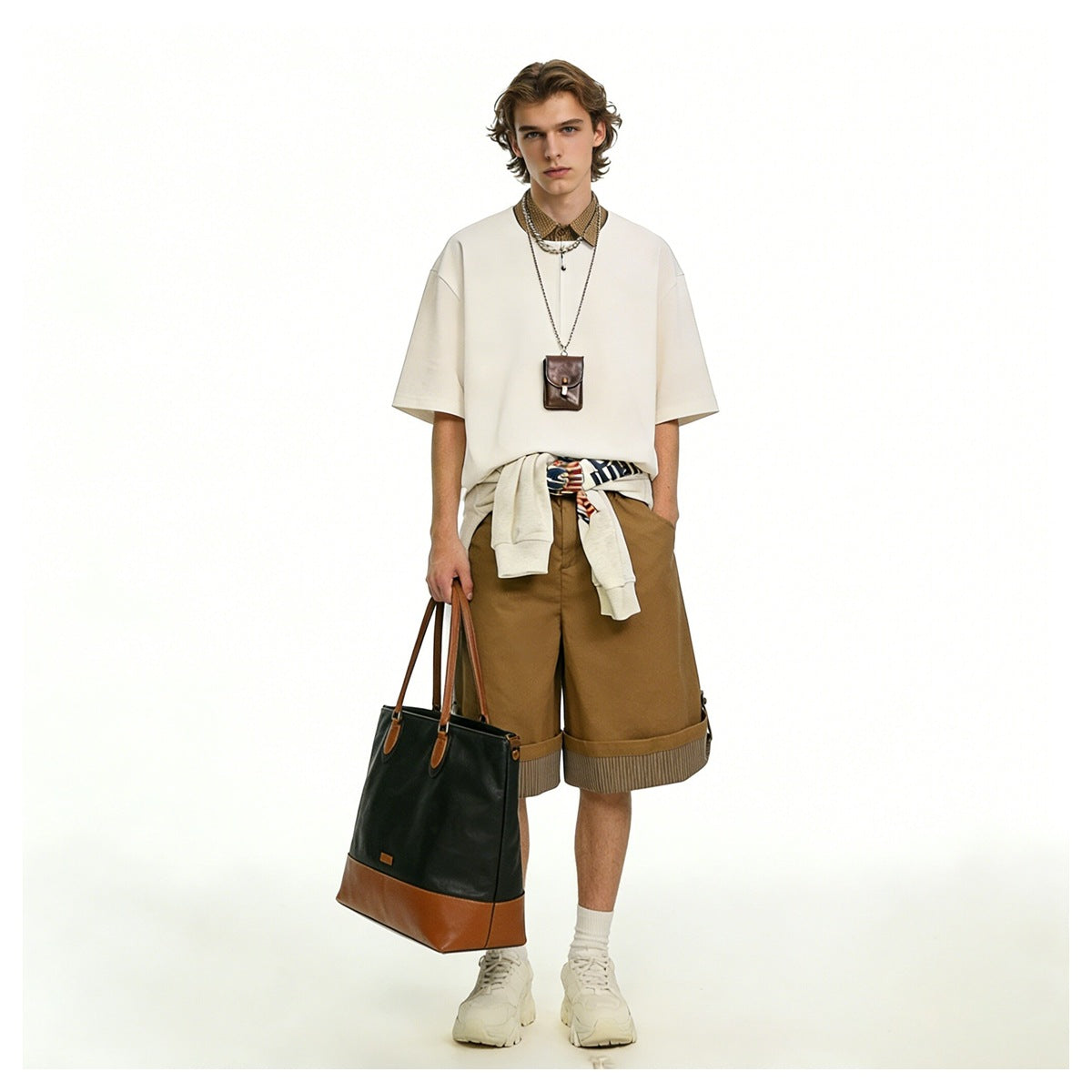 Model wearing camel wide-leg shorts with rolled striped cuffs, styled with a cream shirt and accessories.