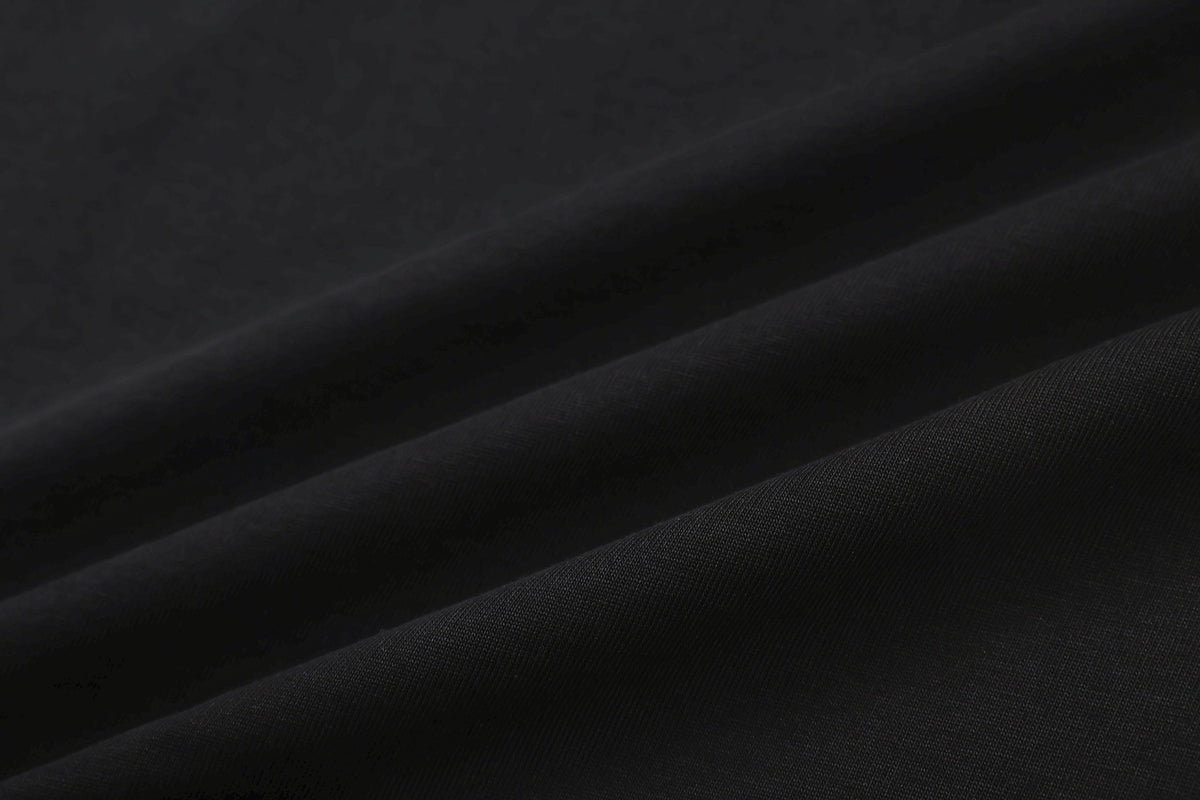 Close-up of dark black fabric with fine diagonal ribbed texture and soft folds.