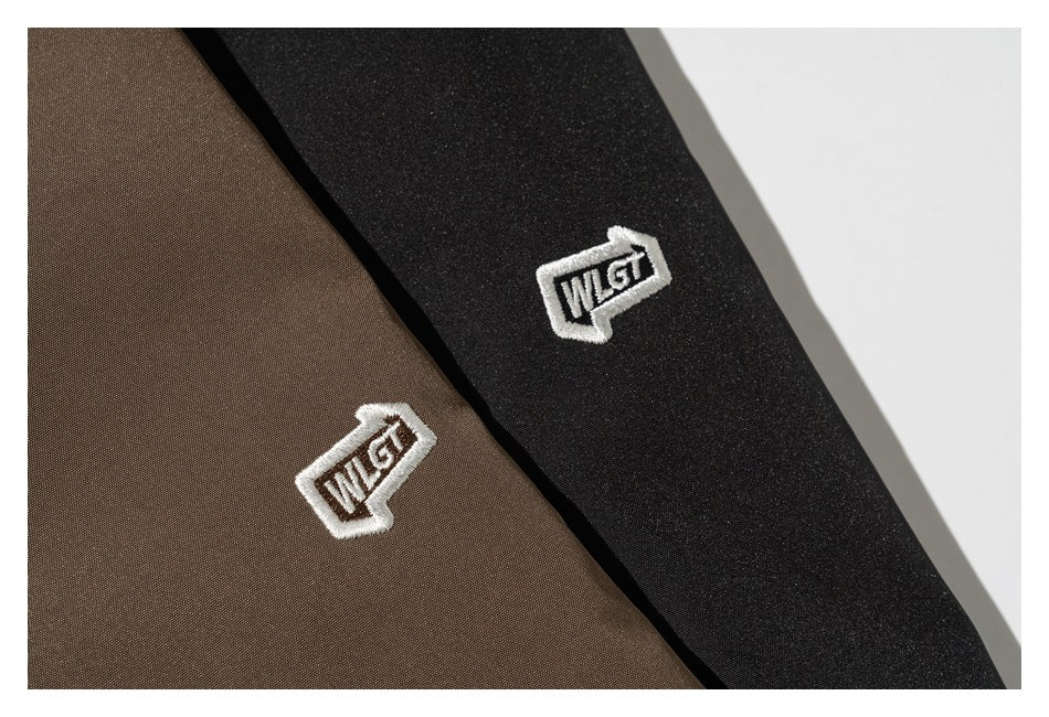Close-up of white embroidered emblems on brown and black garment fabric.