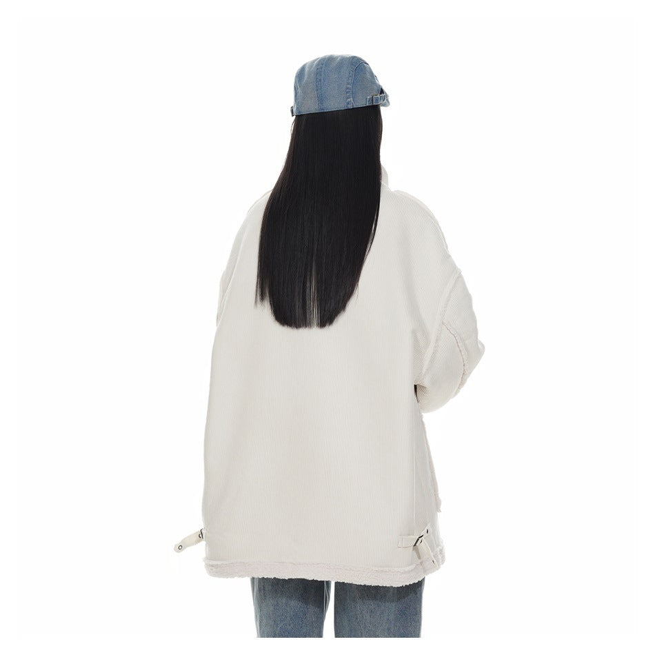 Rear view of a model wearing an oversized ivory corduroy jacket with plush hem trim and loose jeans.