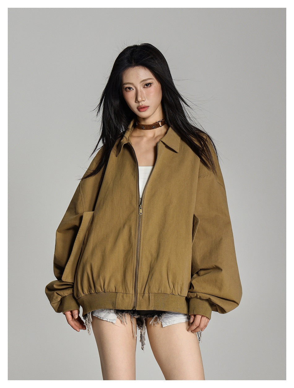 Model wearing an open tan-brown oversized jacket with a pointed collar, front zipper, and gathered ribbed hem.