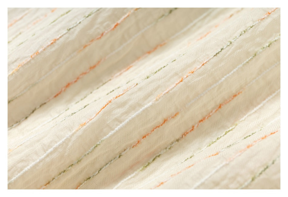 Macro view of raised orange, olive, and white stripes on ivory shirt fabric.