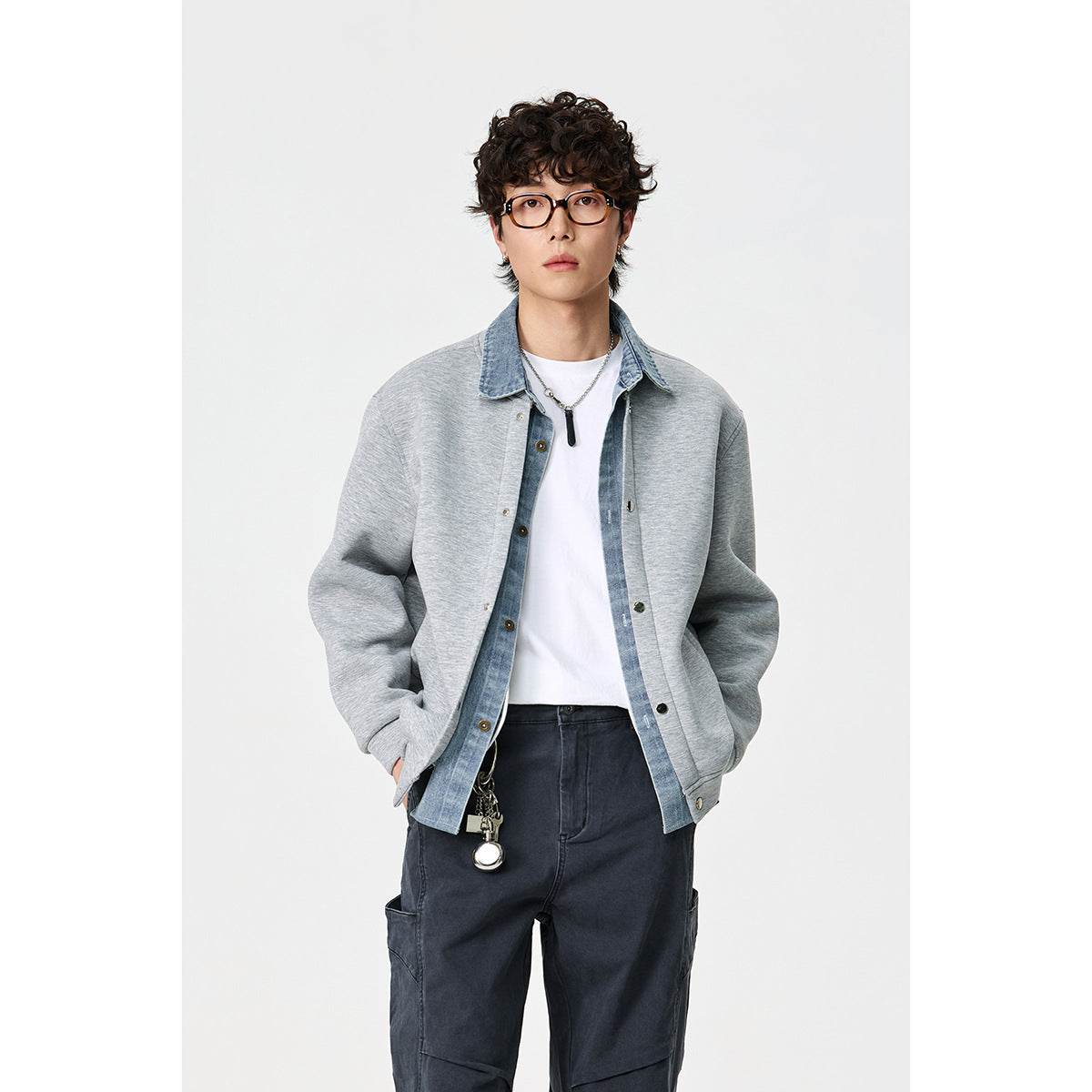 Model wearing a light gray snap-front jacket with a blue denim collar over a white shirt, shown from the front.