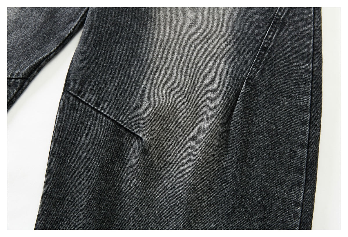 Close-up of dark charcoal washed denim with a diagonal seam and folded fabric edge.