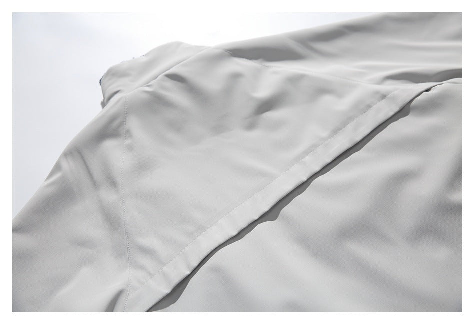 Close-up of light gray garment panels showing a long folded seam and stitching.