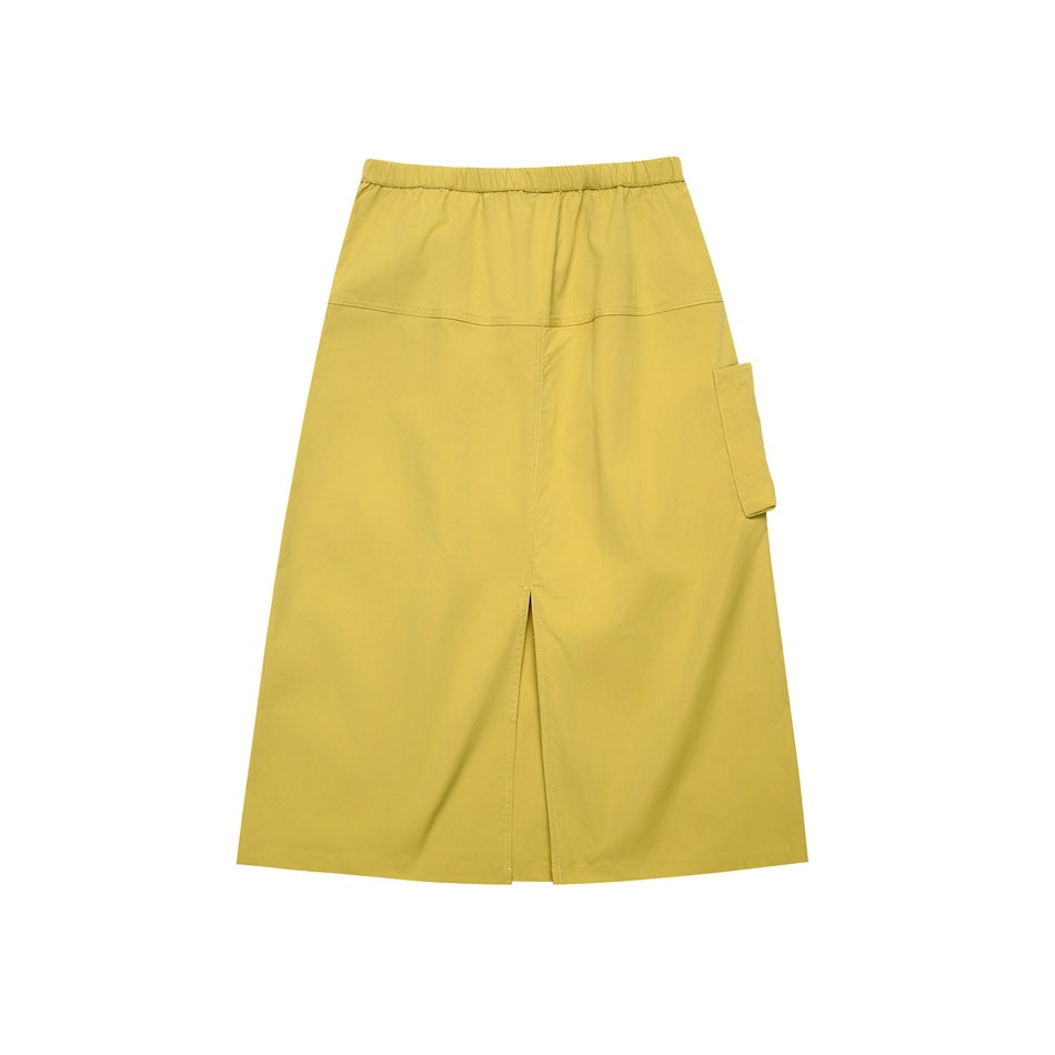 Front view of a mustard yellow long A-line skirt with an elastic waistband, center slit and side cargo pocket.