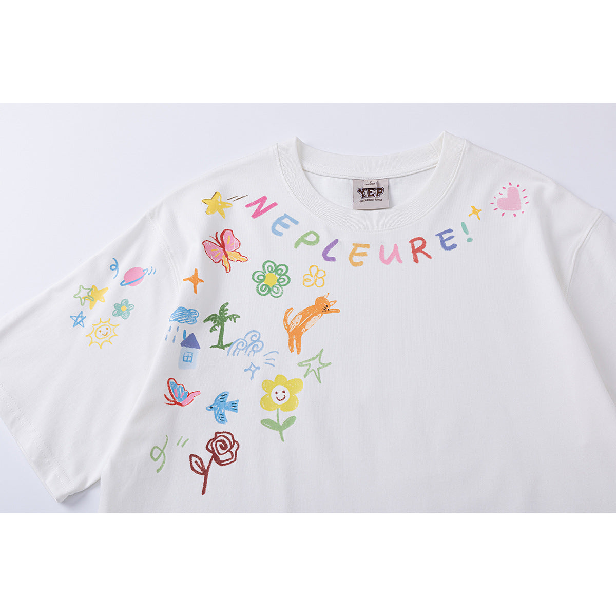 Close-up of a white crew-neck T-shirt with colorful lettering and playful flower, butterfly, and other doodle graphics.
