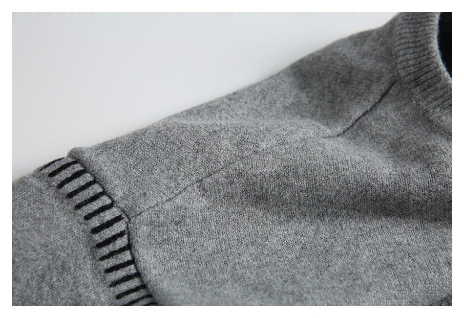 Gray sweater shoulder and sleeve seam detail with black accent stitching at the edge.