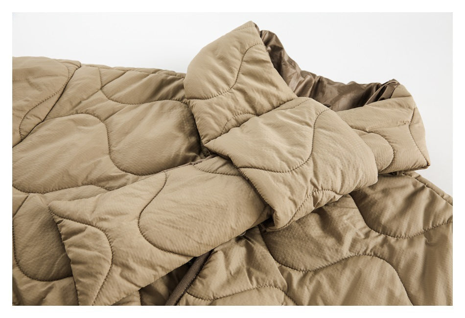 Close-up of a beige quilted jacket showing its wavy stitched panels, sleeve, and cuff.