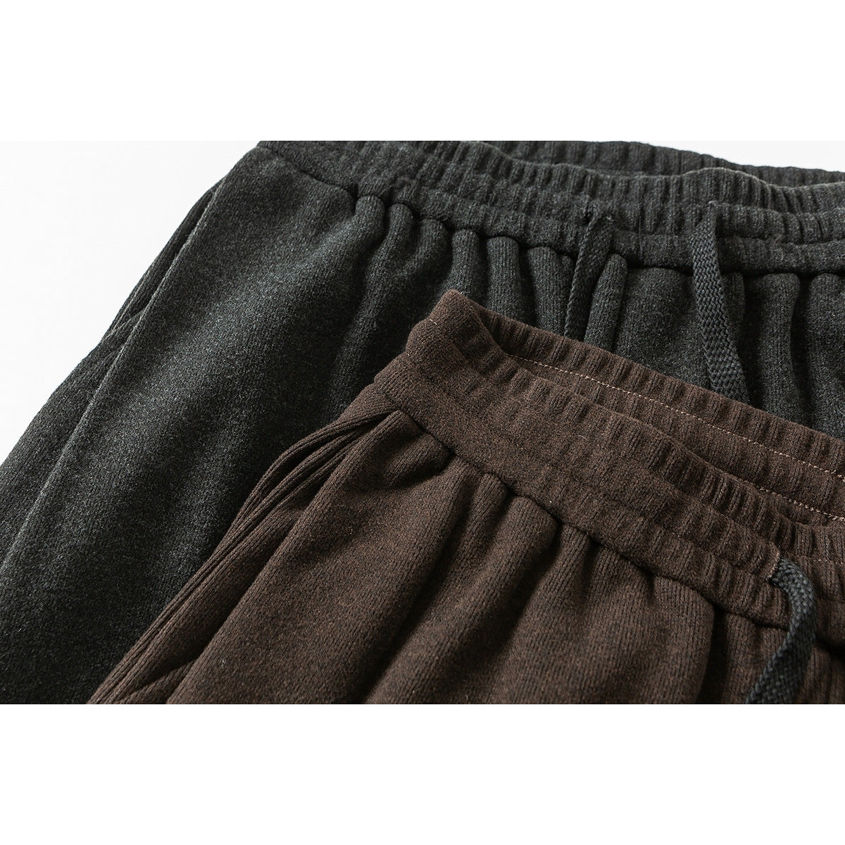 Close-up of charcoal and dark brown pants showing elastic waistbands, gathered fabric and drawstrings.