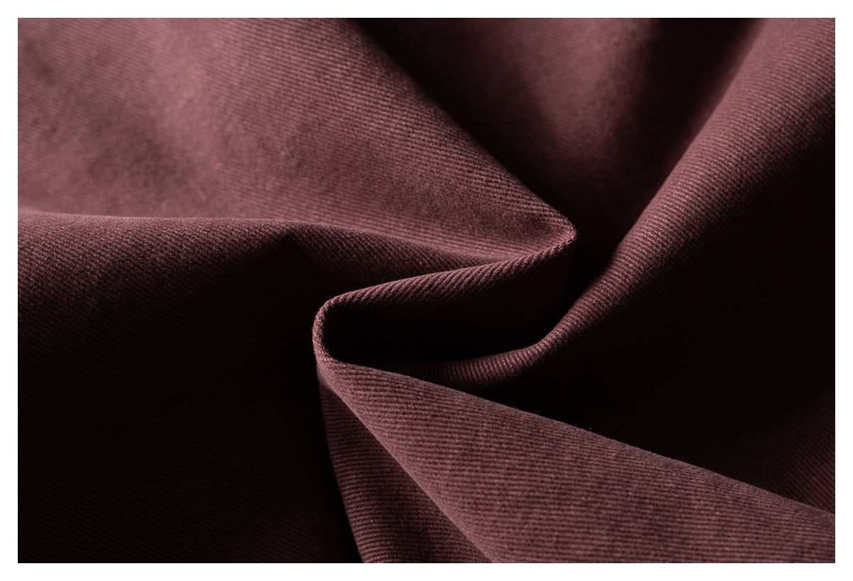 Macro view of burgundy fabric folded to show its fine diagonal texture.