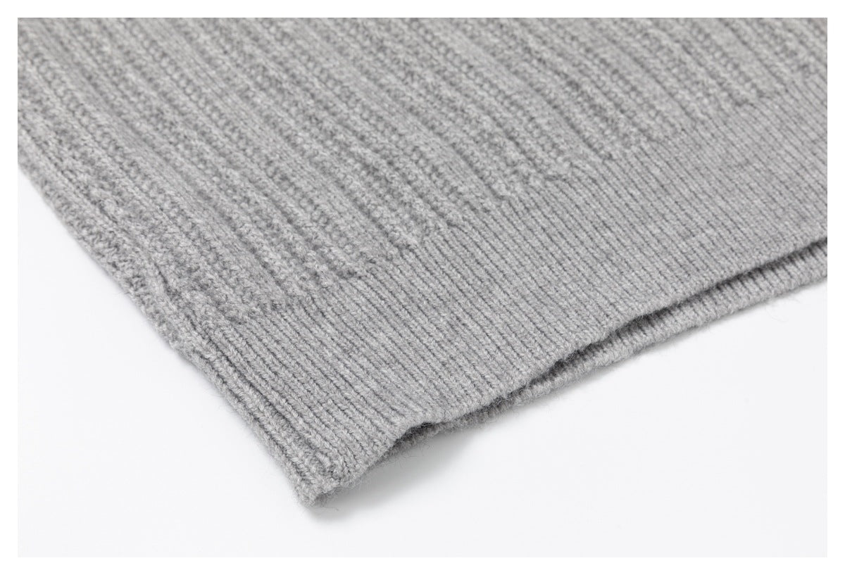 Close-up of the light gray sweater's ribbed hem and textured knit.