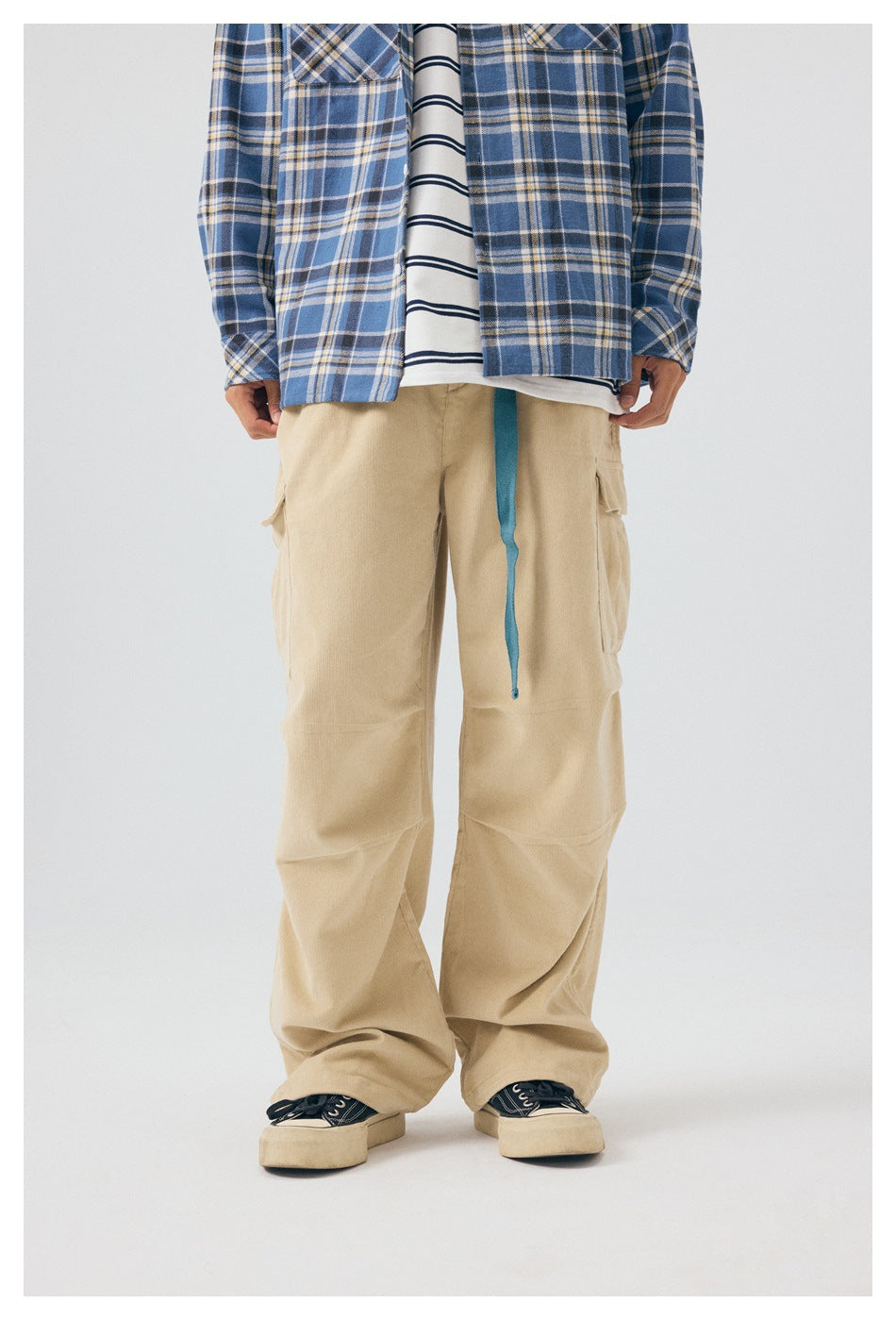Front view of a model wearing loose beige cargo pants with a blue drawstring and flap pockets.