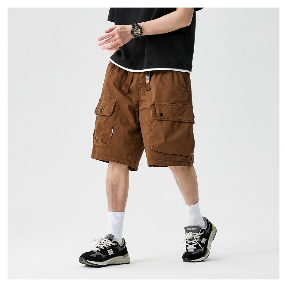 Cropped model wearing brown cargo shorts with large button-flap pockets, shown from the front at an angle.