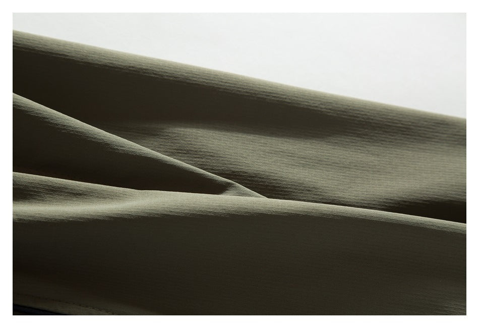 Close-up of olive-gray fabric arranged in soft folds, showing its fine surface texture.