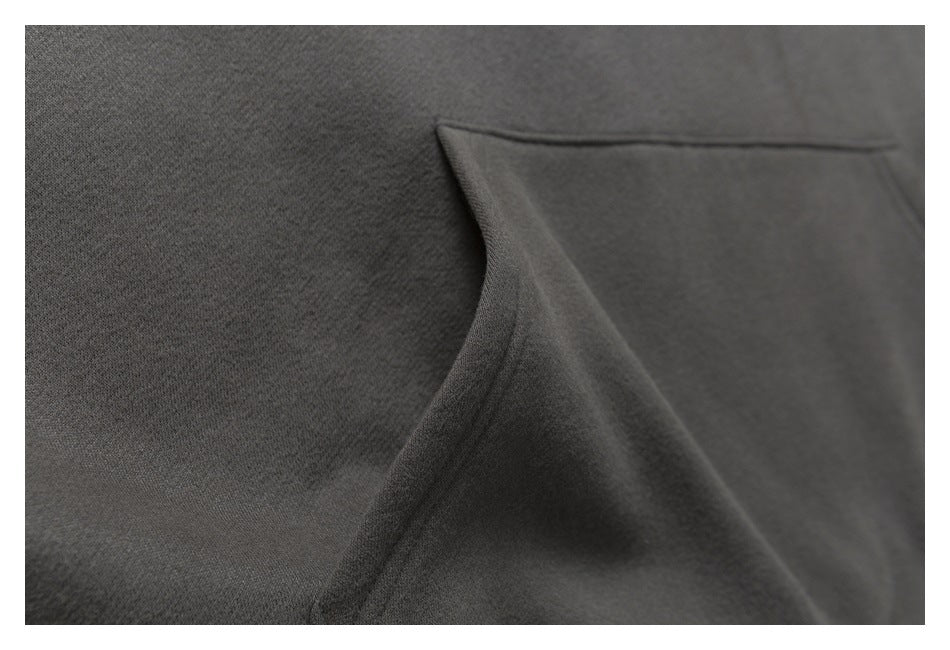 Close-up of a dark charcoal garment showing a curved pocket opening and stitching.