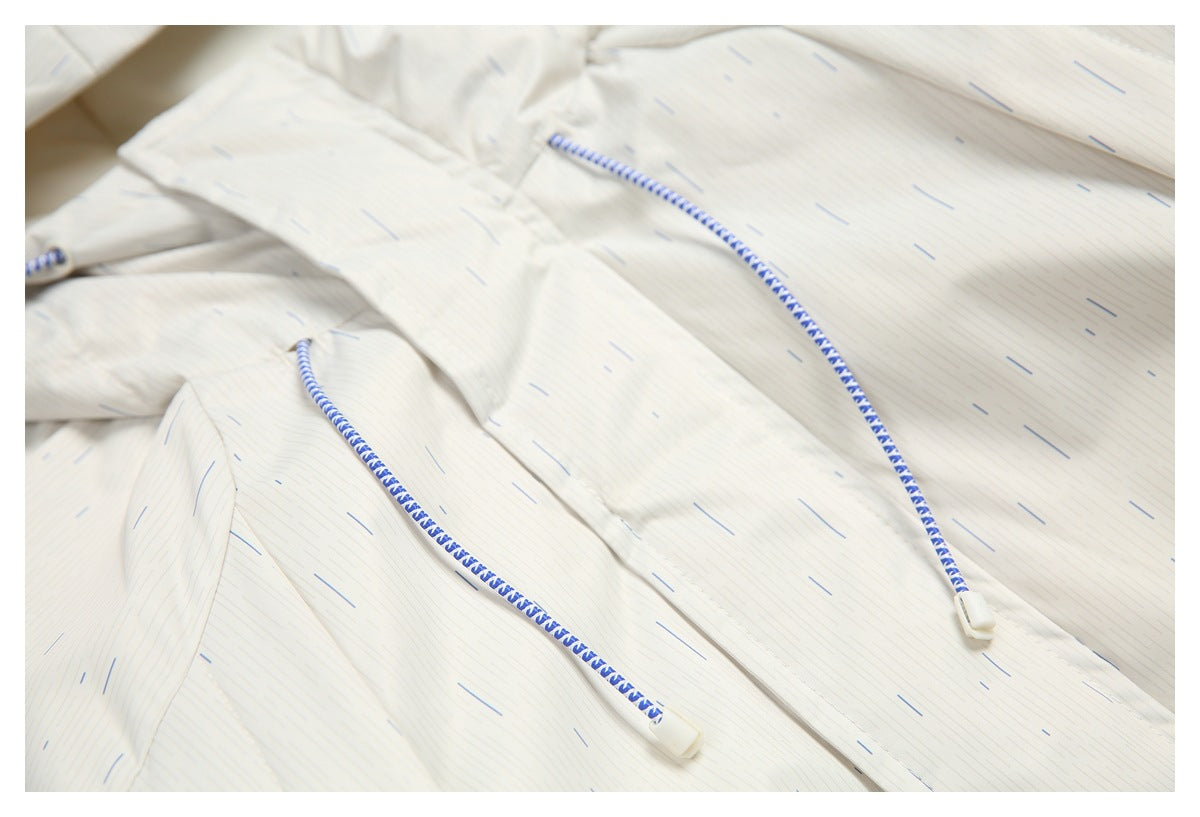 Close-up of an off-white garment with fine blue-gray dash marks and blue-and-white braided drawcords with white tips.