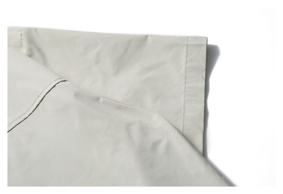 Close-up of folded pale gray shirt fabric showing a straight stitched edge and curved seam.