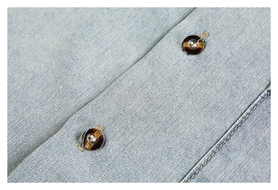 Close-up of pale washed denim with two brown buttons on a diagonal front placket.