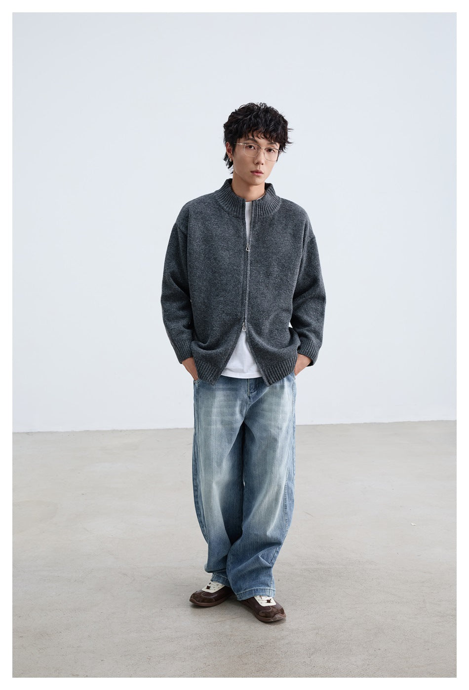 Full-length model wearing a charcoal gray zip-front cardigan with ribbed trim and loose blue jeans.