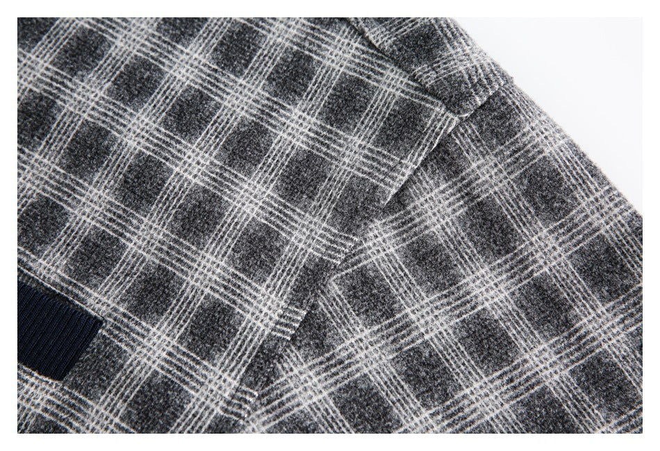 Close-up of a stitched seam in charcoal gray plaid fabric beside dark ribbed trim.