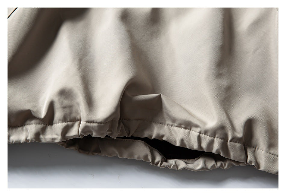 Close-up of a beige garment’s gathered, stitched hem with a dark opening beneath.