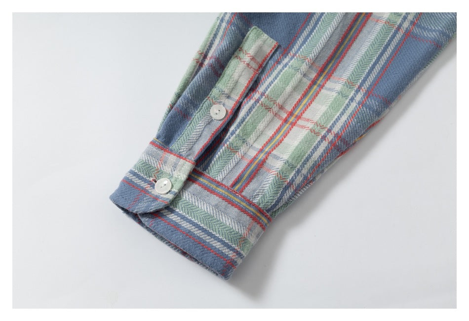 Close-up of a blue plaid shirt sleeve and buttoned cuff.