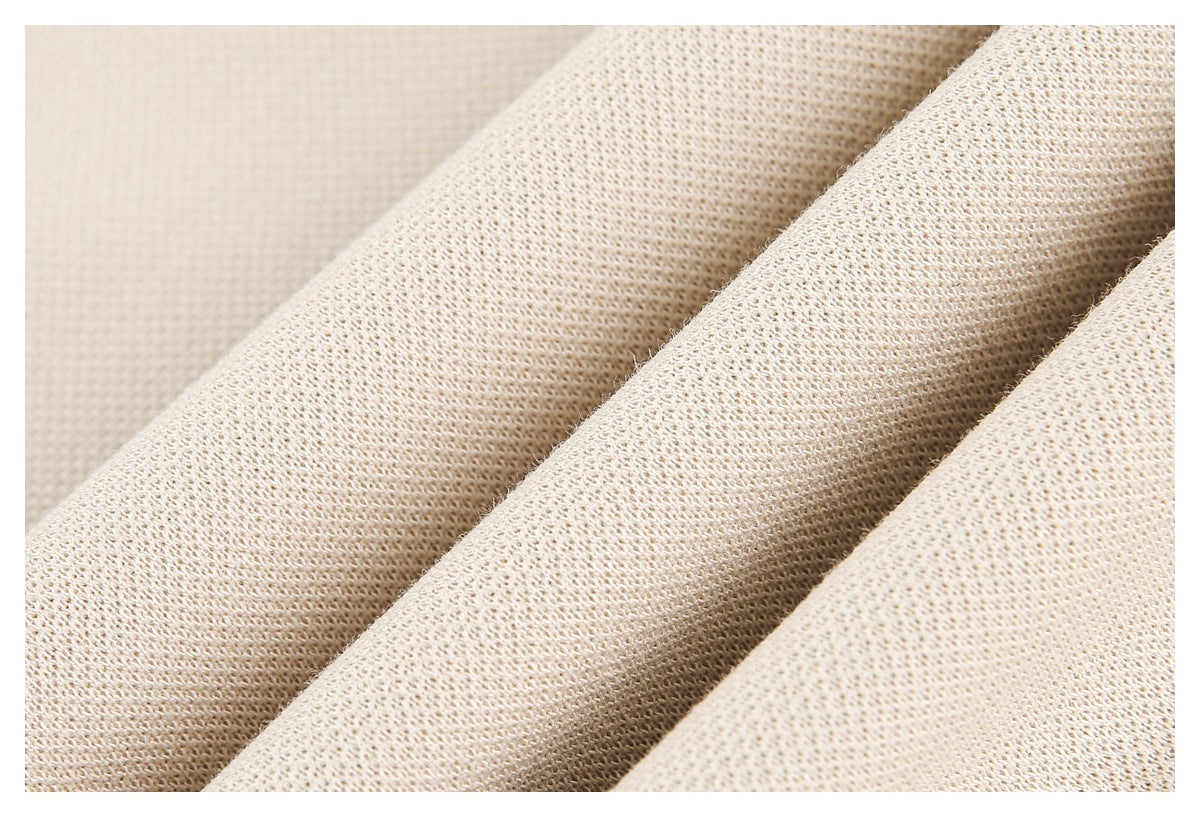 Close-up of cream knit fabric arranged in folds, showing its textured weave.