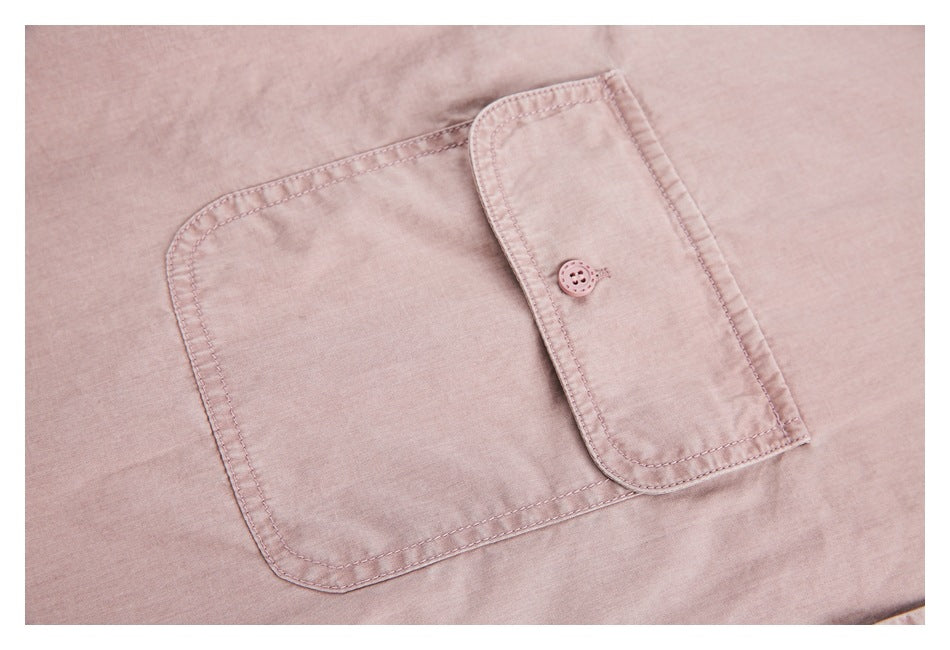 Close-up of a dusty pink shirt's patch pocket and buttoned pocket flap.