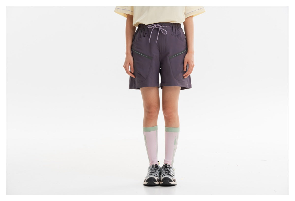 Front view of a model wearing dark plum drawstring shorts with angled zip pockets.