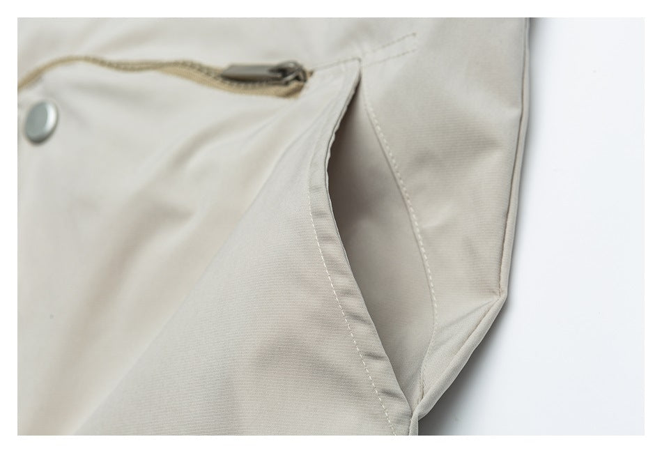Close-up of a light beige jacket pocket opening with a zipper and snap detail.