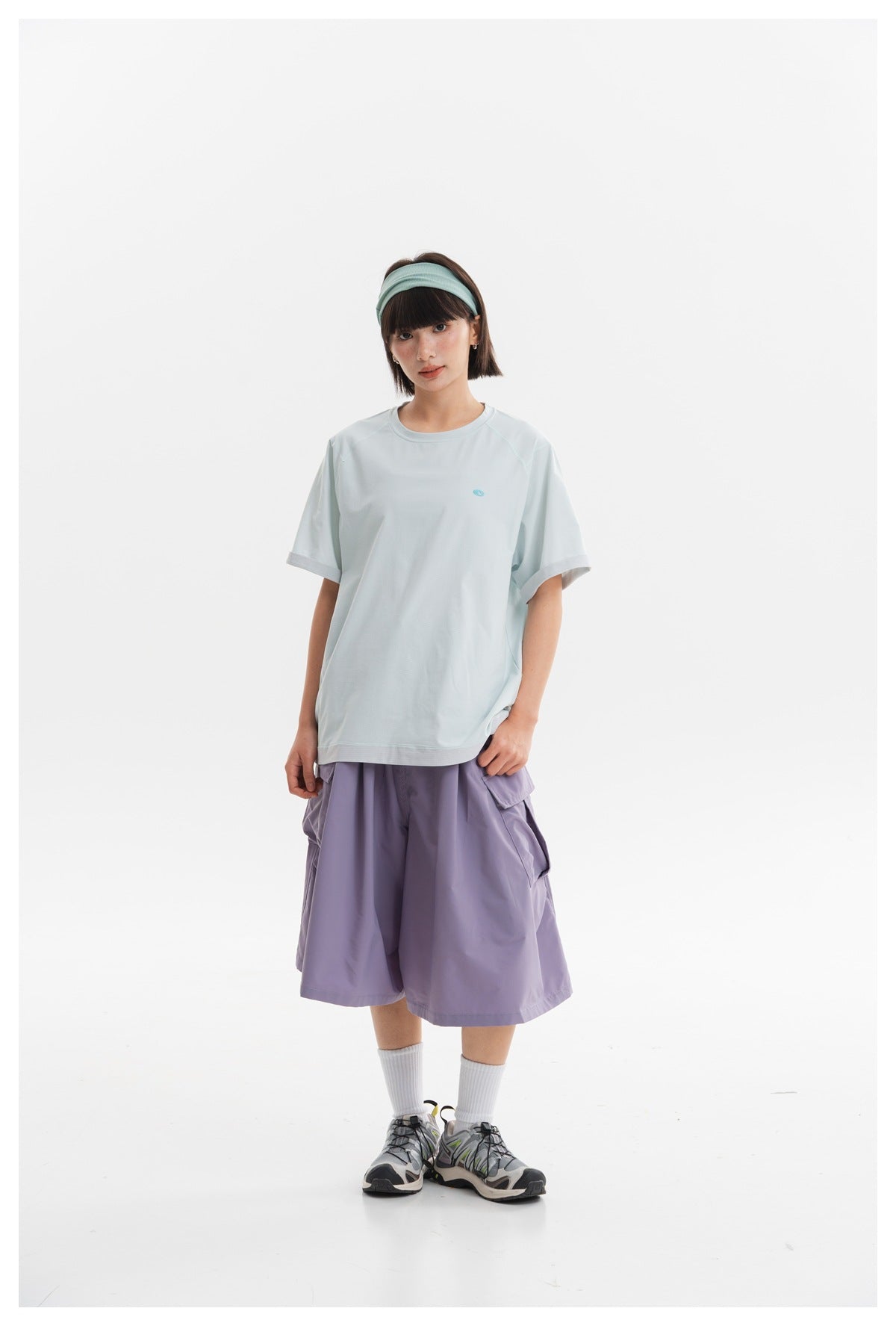 Full-length front view of a model wearing a pale blue short-sleeve tee and loose lavender cargo shorts.