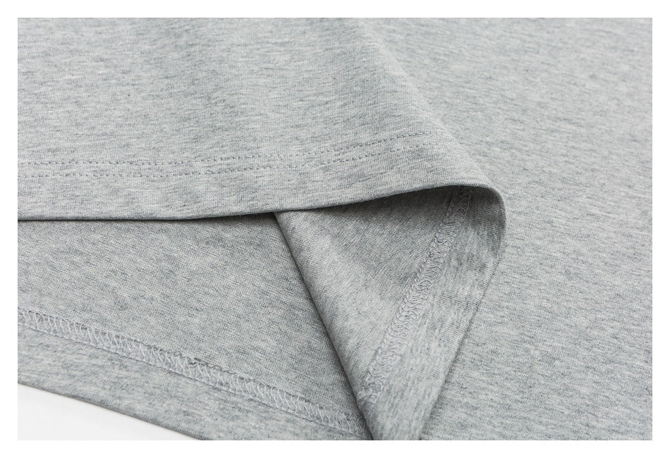 Close-up of a heather-gray T-shirt hem, showing the folded edge and overlock stitching.