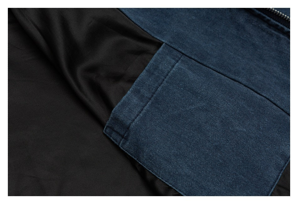 Close-up of a blue denim pocket panel against black lining, with part of a zipper visible.
