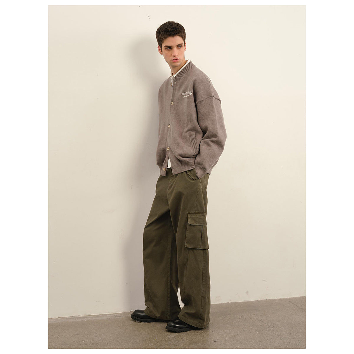 Model wearing a taupe button-front cardigan with chest embroidery and olive cargo trousers, shown full length.