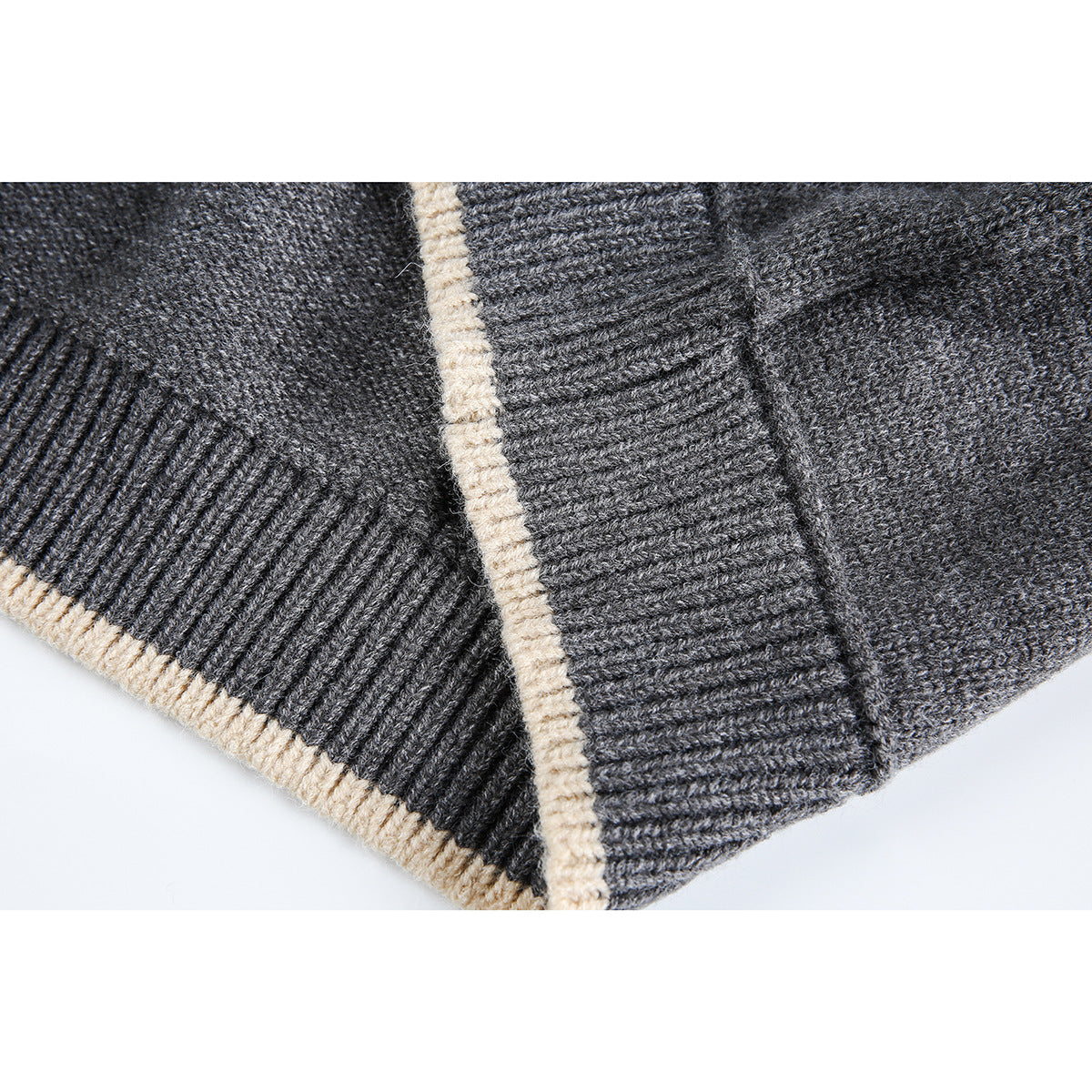 Close-up of charcoal sweater ribbed edging with narrow cream trim along the hem and cuff.