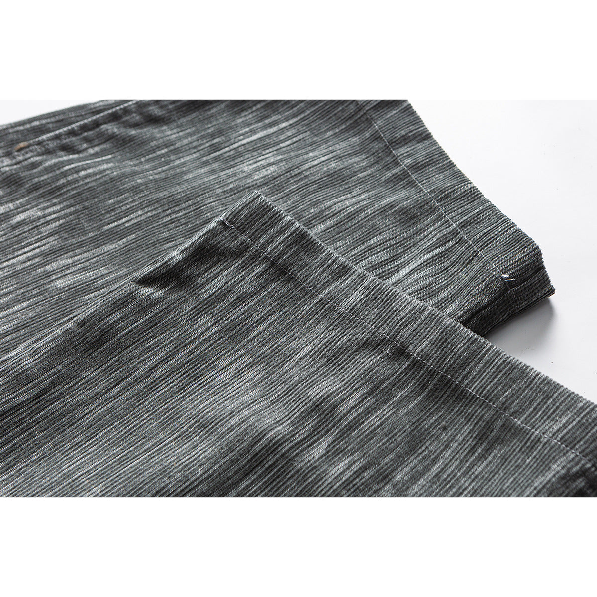 Close-up of the gray trousers' textured fabric and stitched hem.
