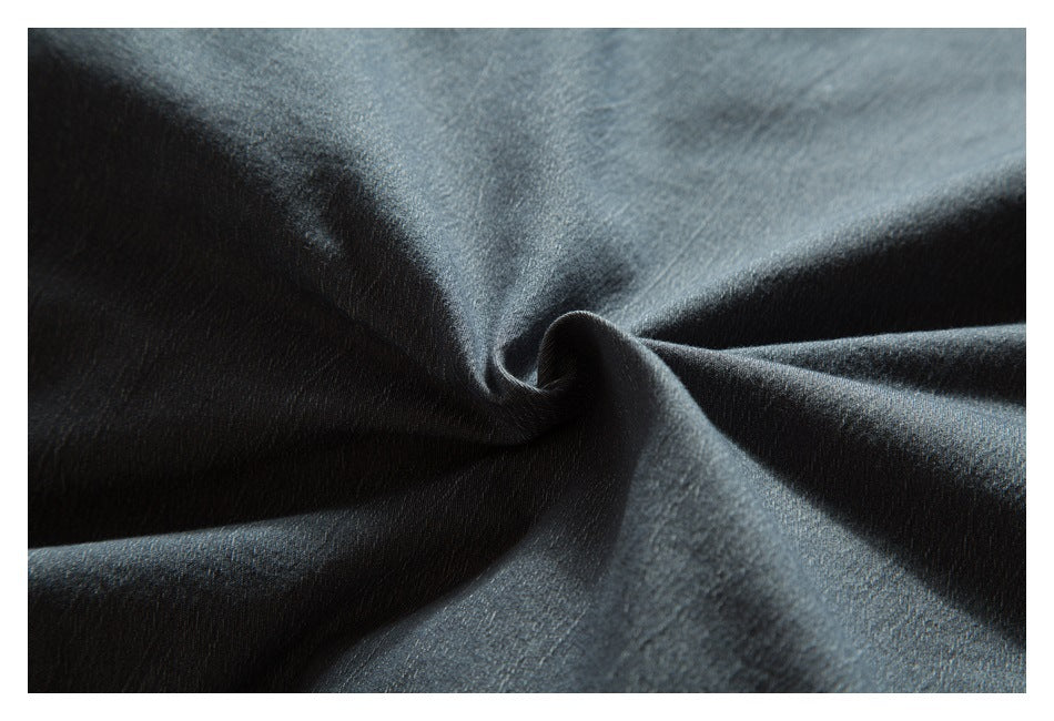 Close-up of dark gray fabric gathered into folds, showing its fine surface texture.