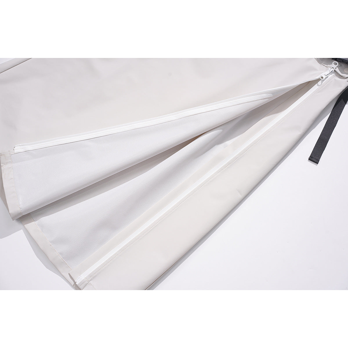 Close-up of an off-white skirt opened to show its long white zipper and layered panels.
