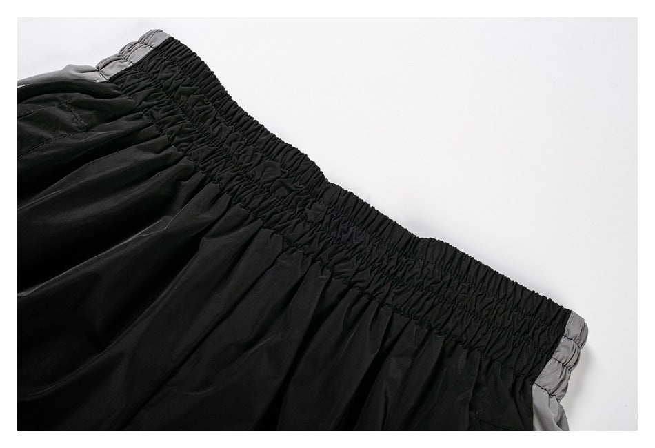 Close-up of the gathered elastic waistband and upper fabric of black shorts with gray accents.