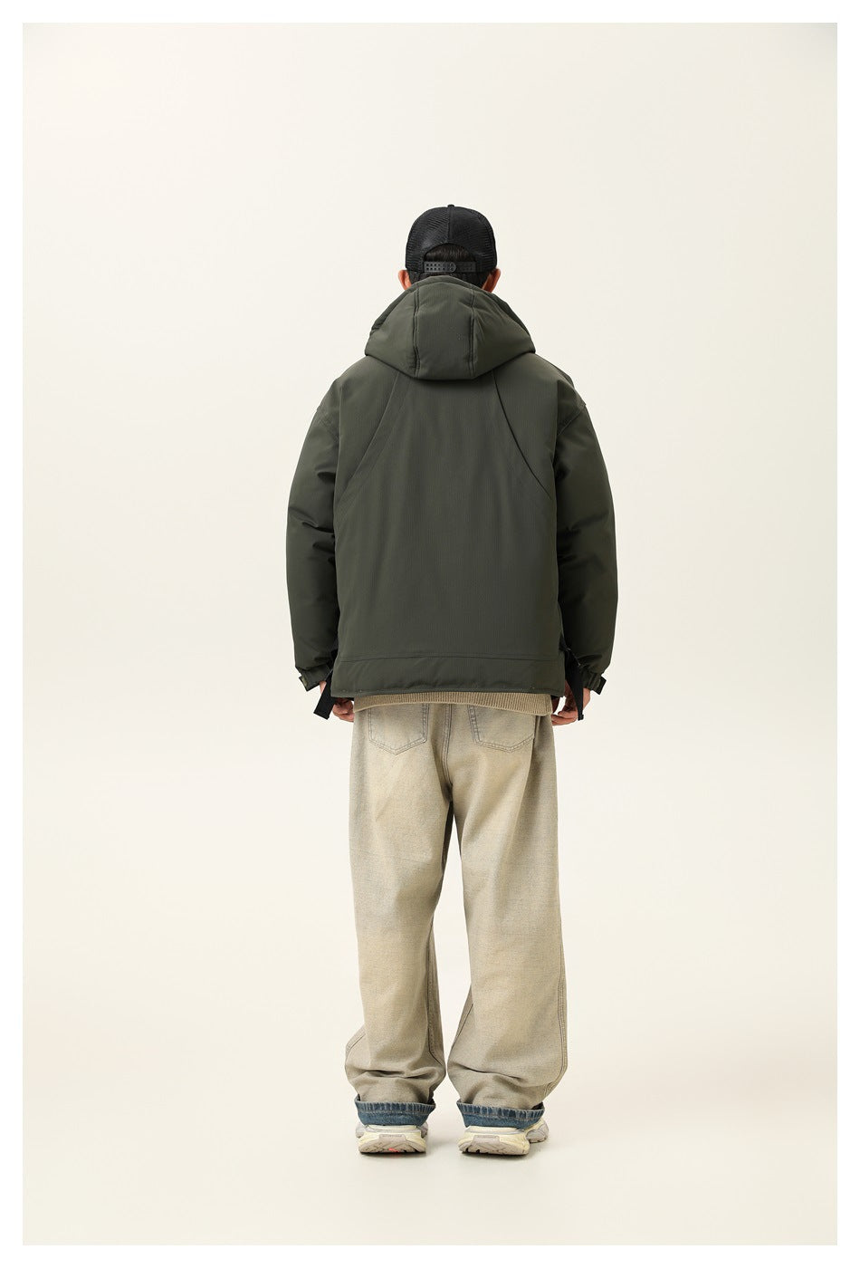 Back view of model in army green hooded puffer jacket with curved seam panels and wide-leg pants