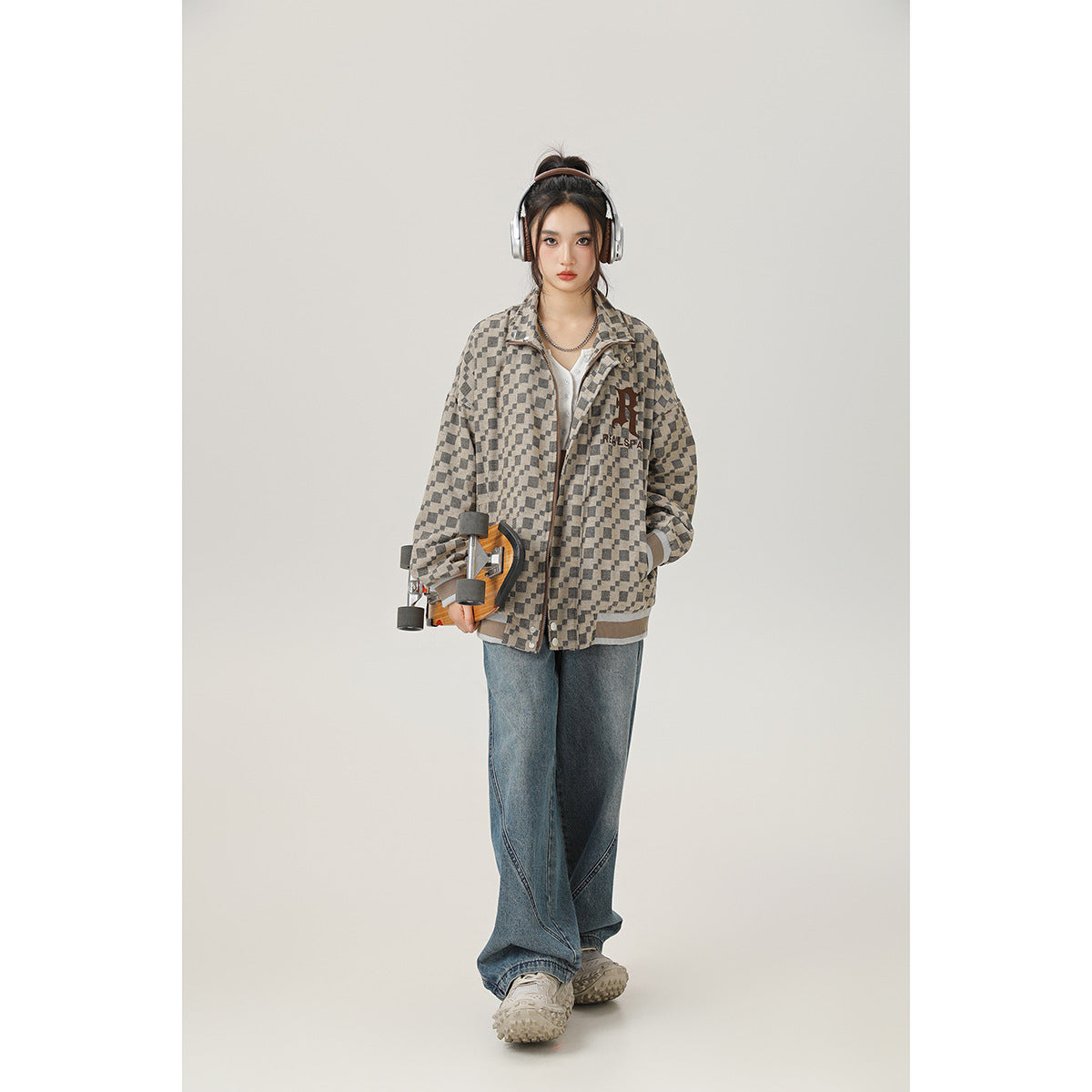 Model wearing an oversized beige-and-charcoal checker-pattern jacket with a snap front and ribbed trim.