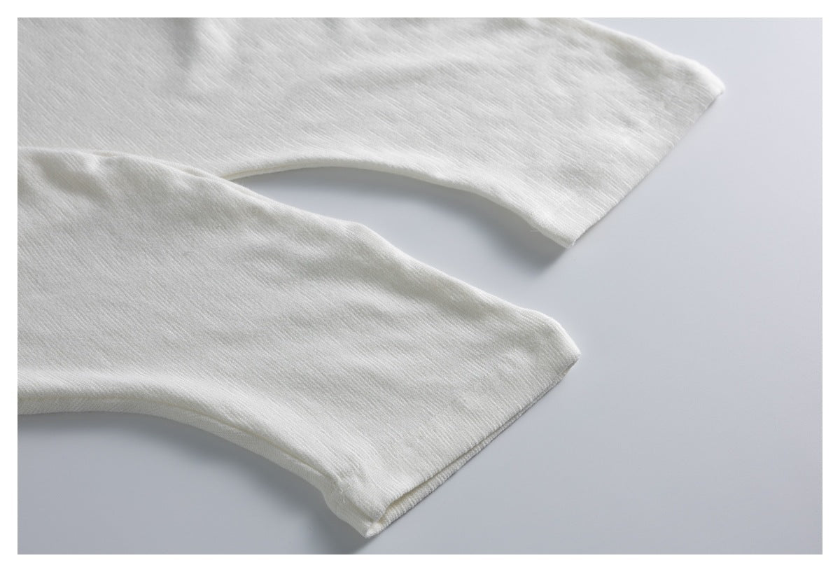 Close-up of two white garment sleeve edges laid flat against a pale background.