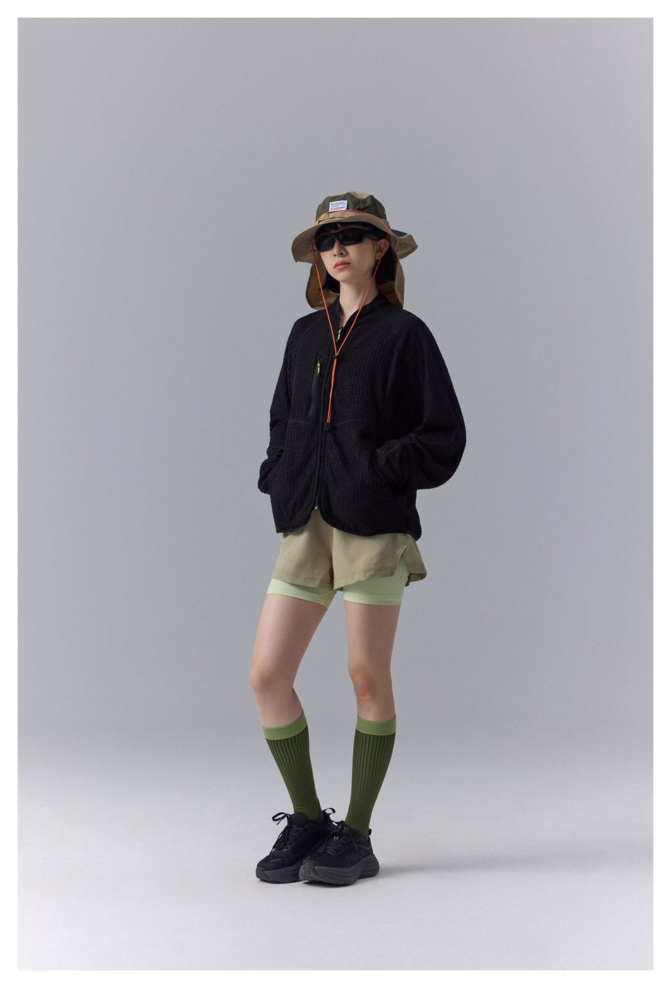 Full-length front view of a model wearing a black textured zip jacket and shorts.